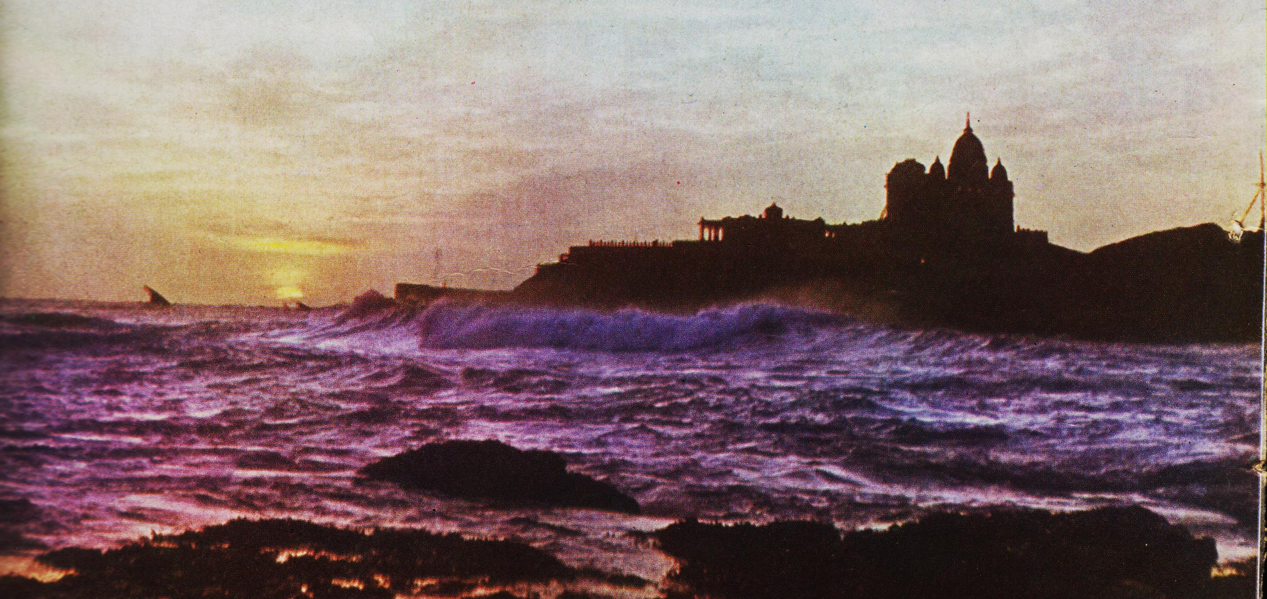 A silhouette of the Vivekananda Rock Memorial as seen against the golden light of the rising sun.